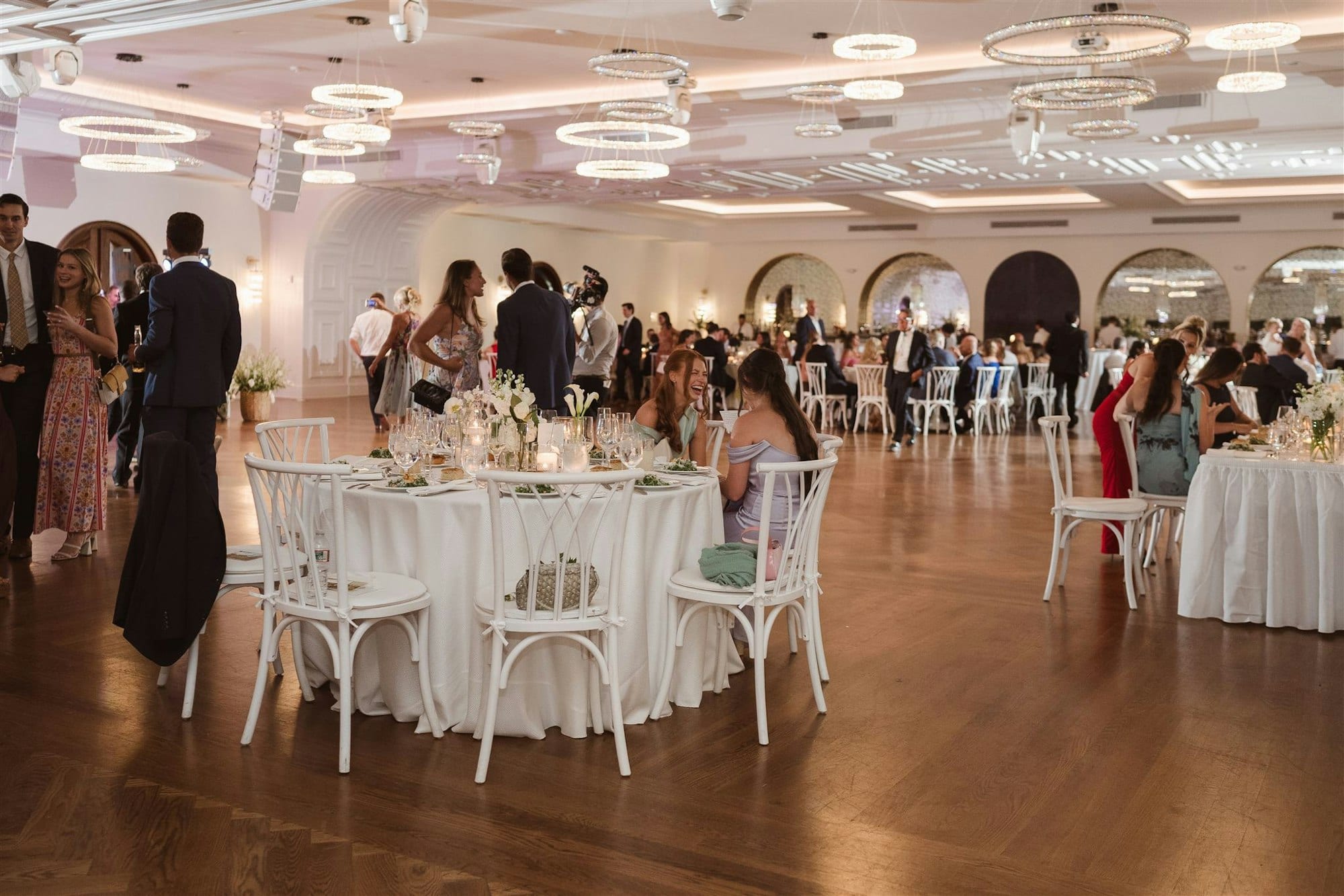 The grand ballroom at TillingHouse set for a wedding reception with round tables and arched windows