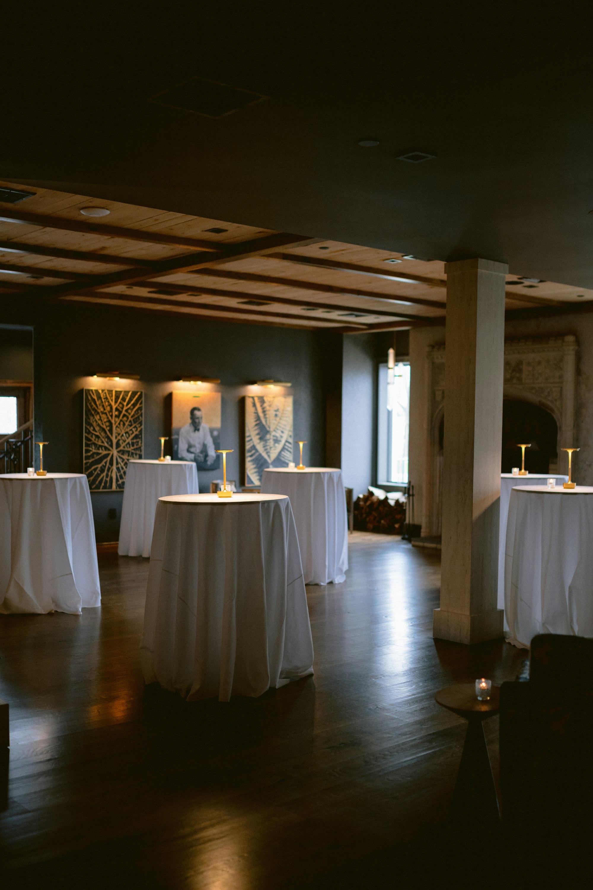 The warmly lit ballroom set with round tables for an evening event at TillingHouse