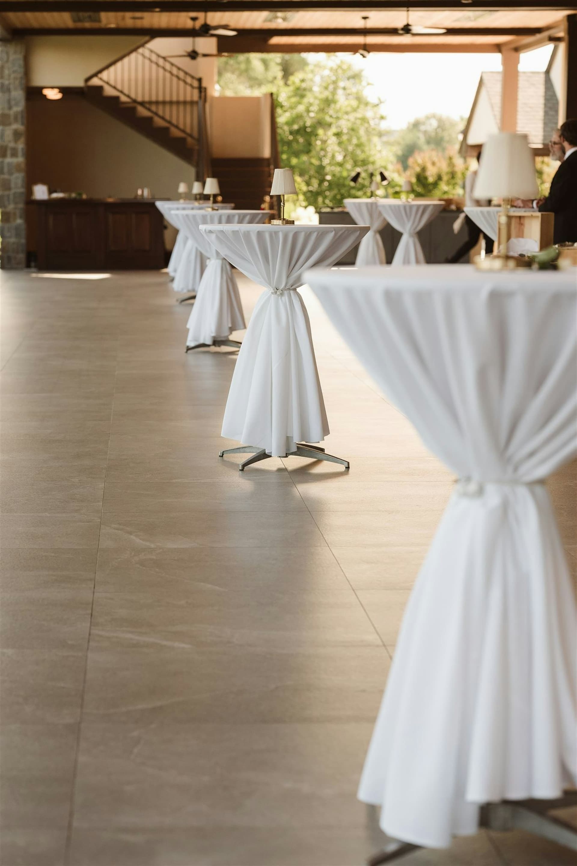 Cocktail hour with white-draped highboy tables in the arched interior at TillingHouse