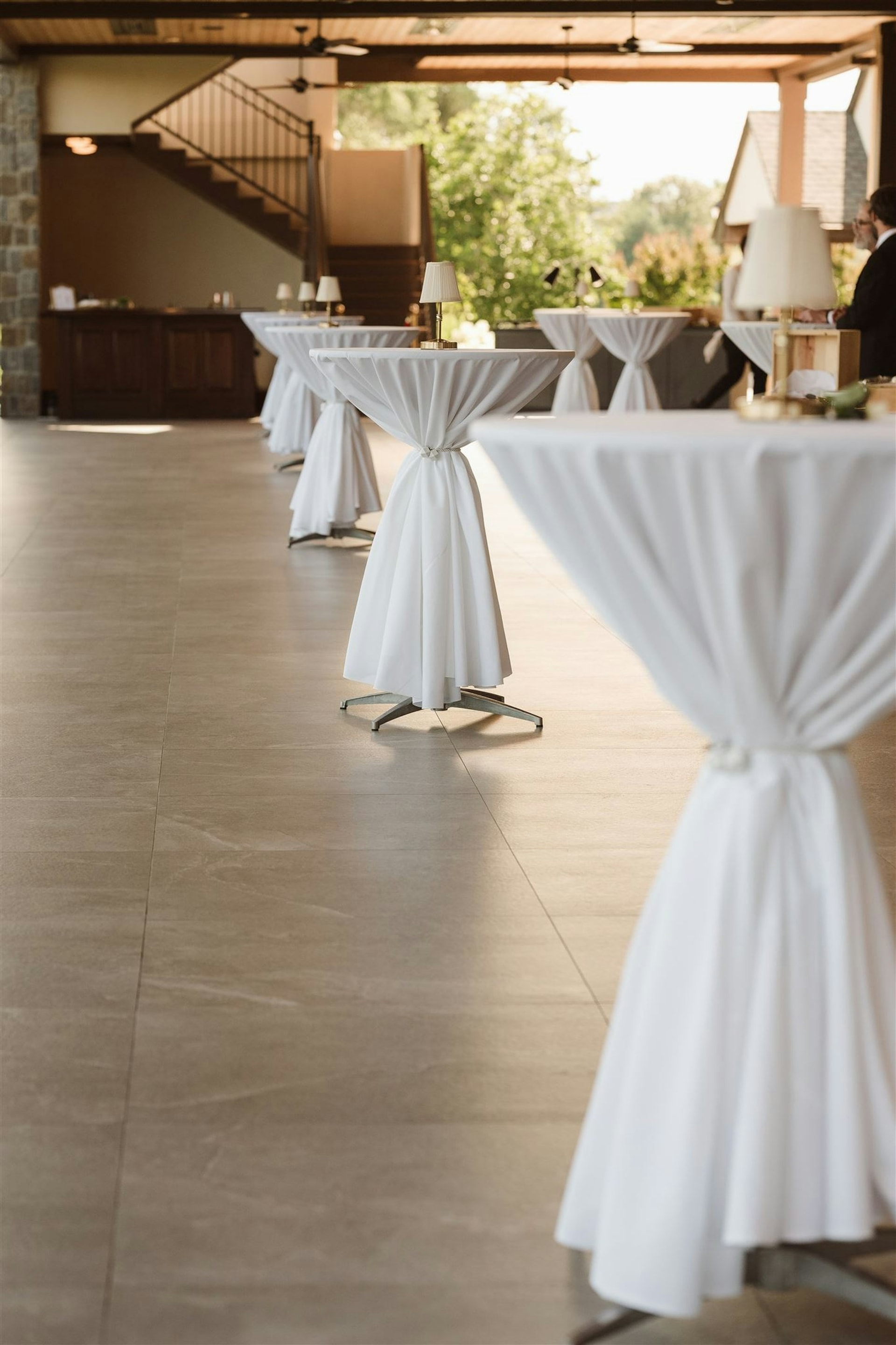 Cocktail hour with white-draped highboy tables in the arched interior at TillingHouse
