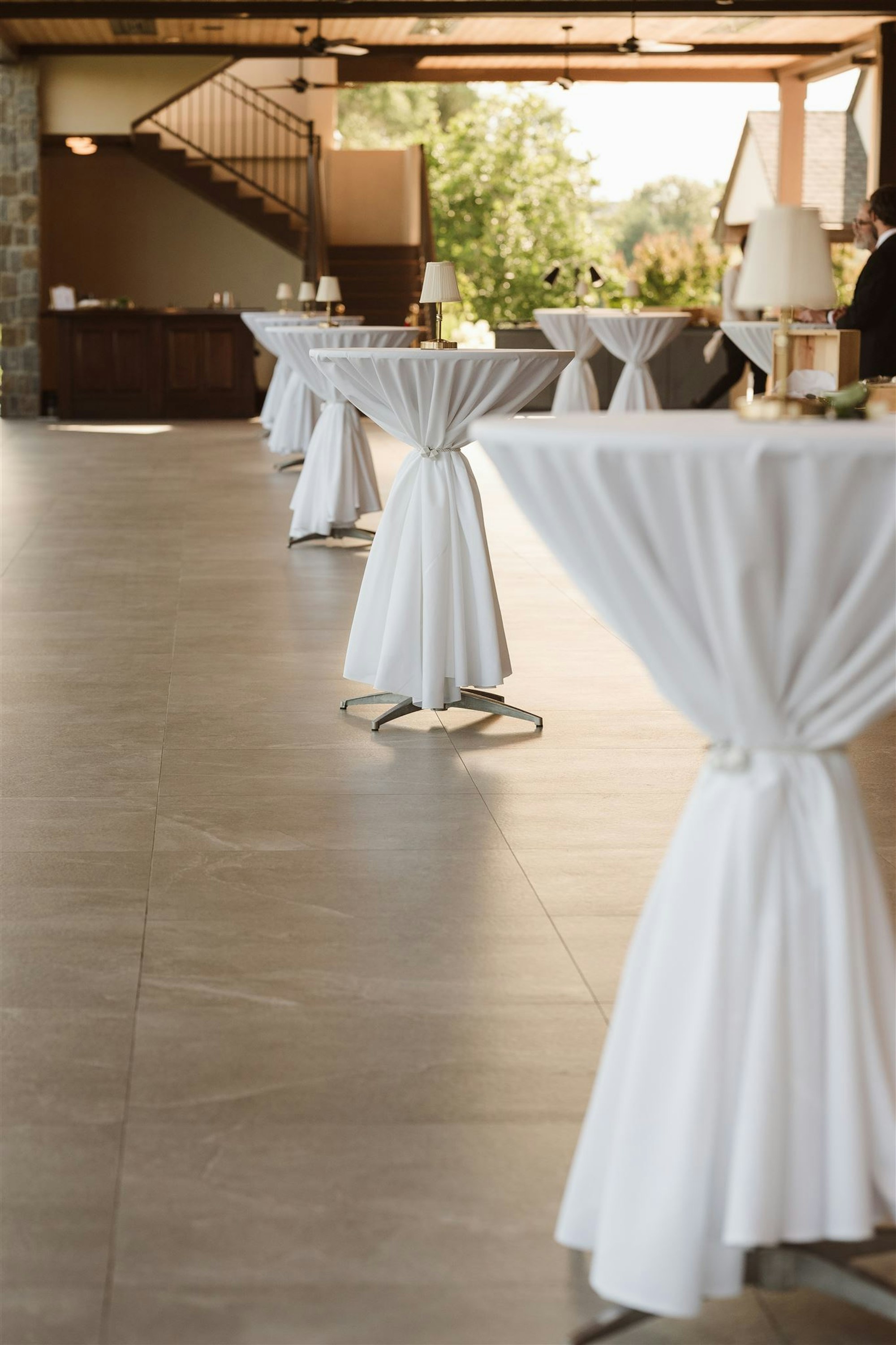 Cocktail hour with white-draped highboy tables in the arched interior at TillingHouse