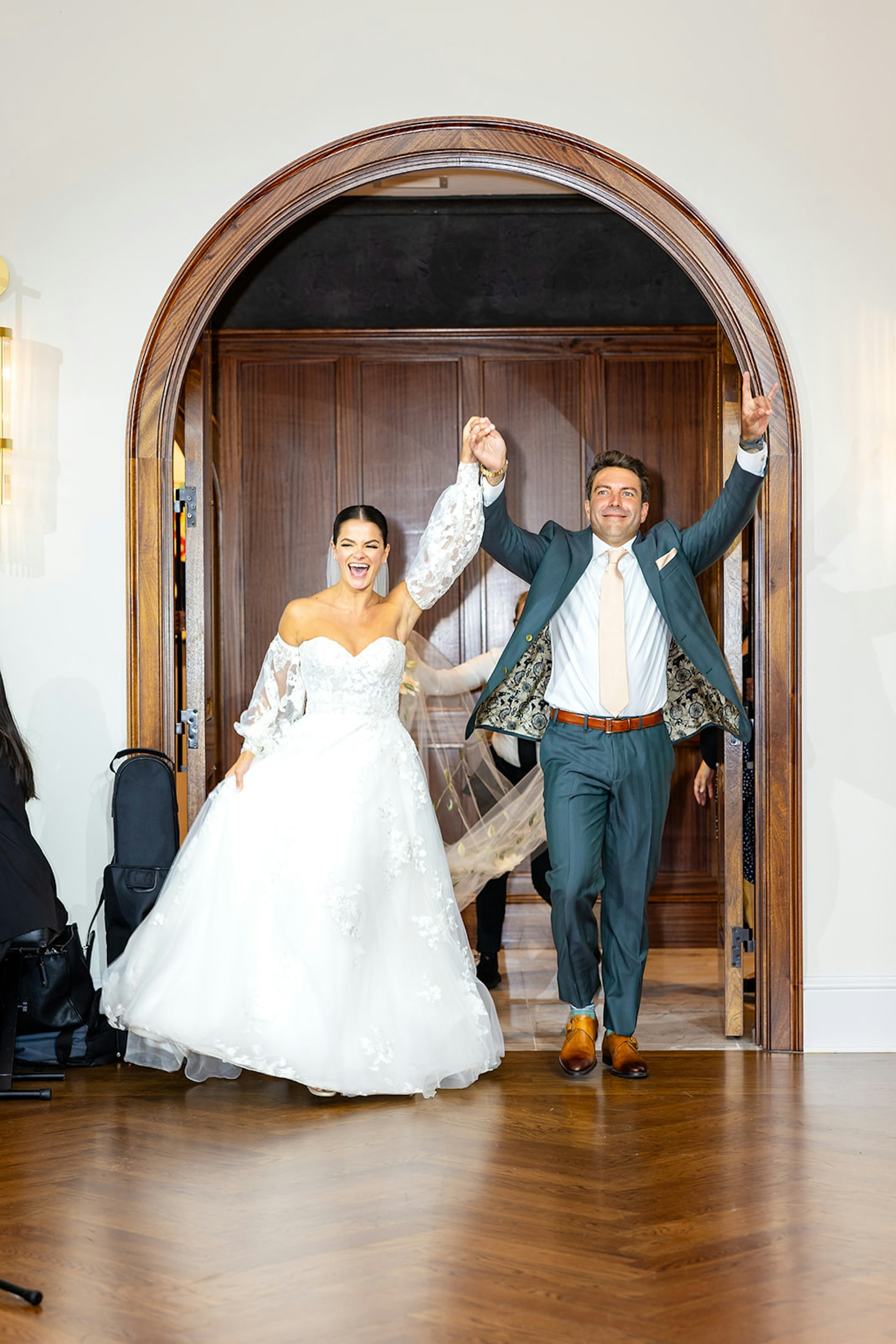 A newlywed couple making their grand entrance through the arched doors at TillingHouse