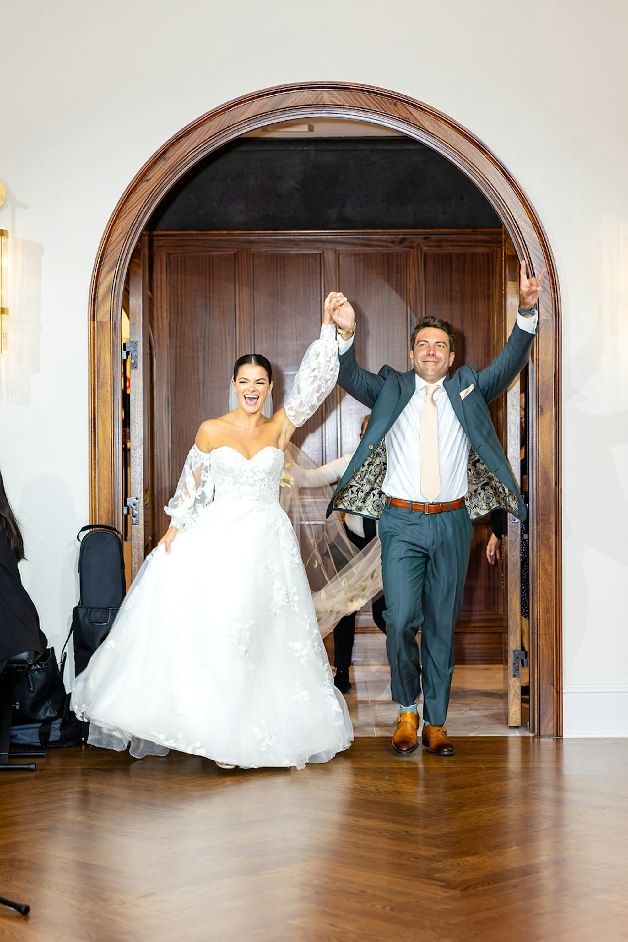 A newlywed couple making their grand entrance through the arched doors at TillingHouse