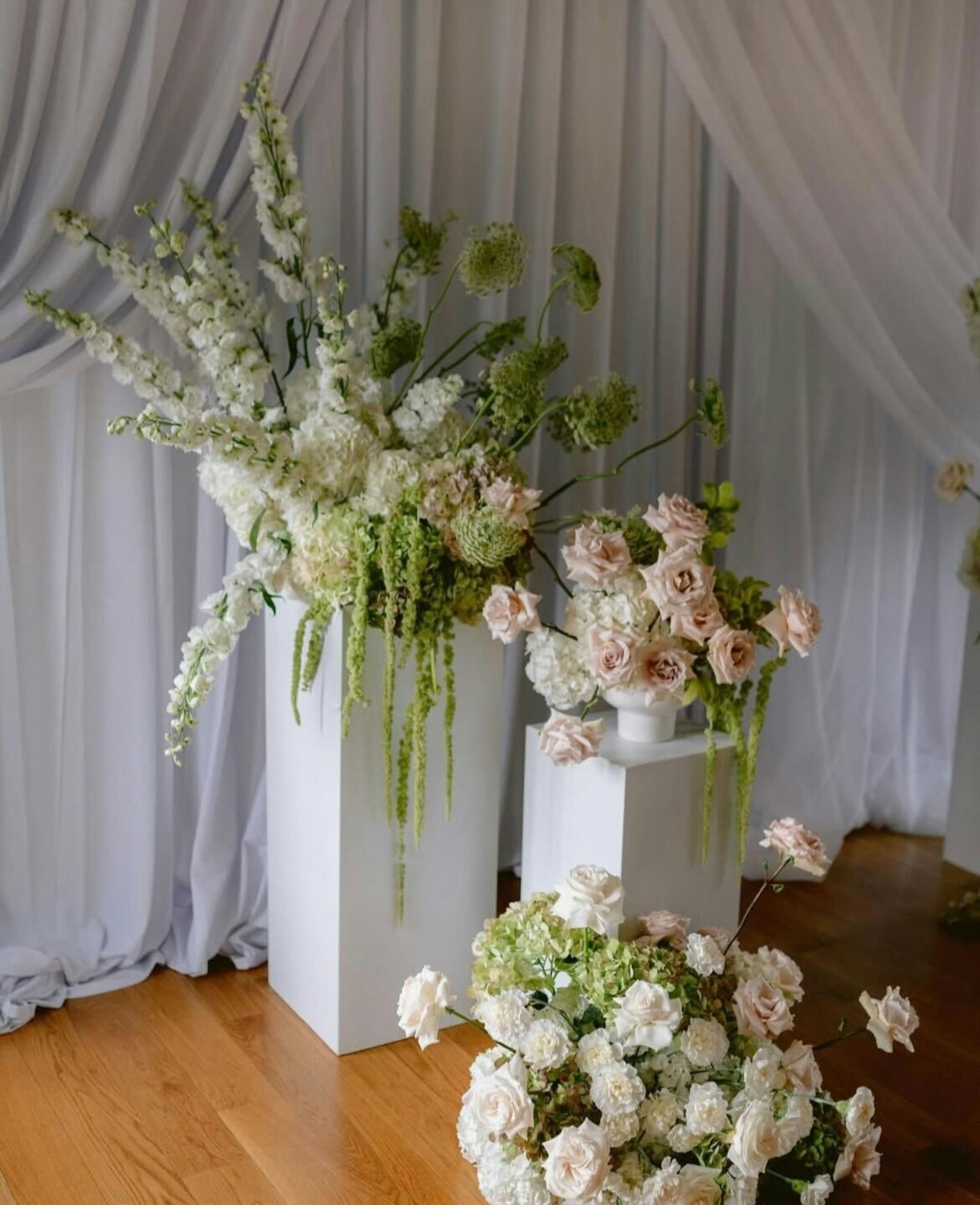 A tall white floral arrangement against ceremony draping at TillingHouse