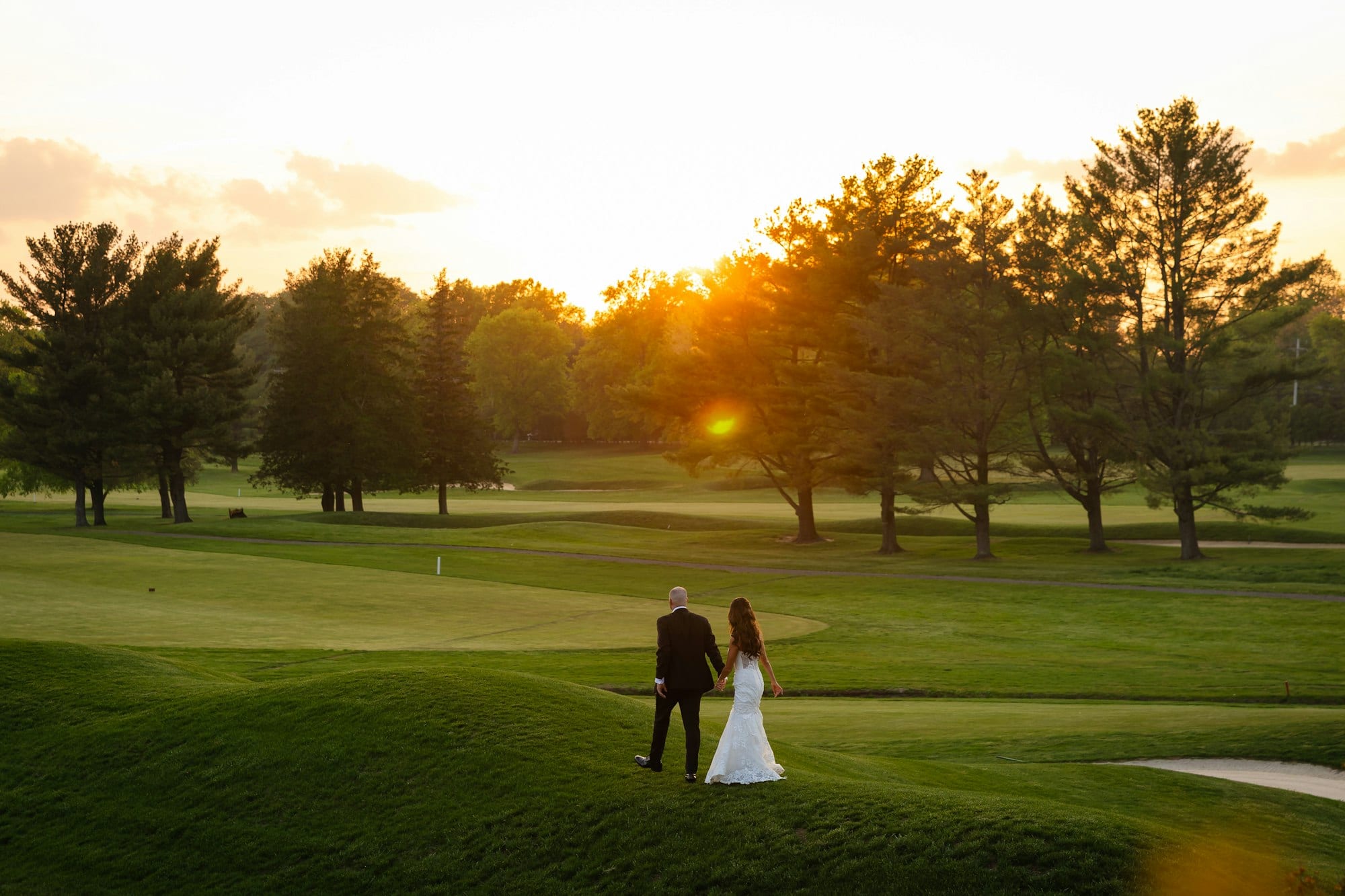 A couple walking the golf-course grounds at sunset at TillingHouse