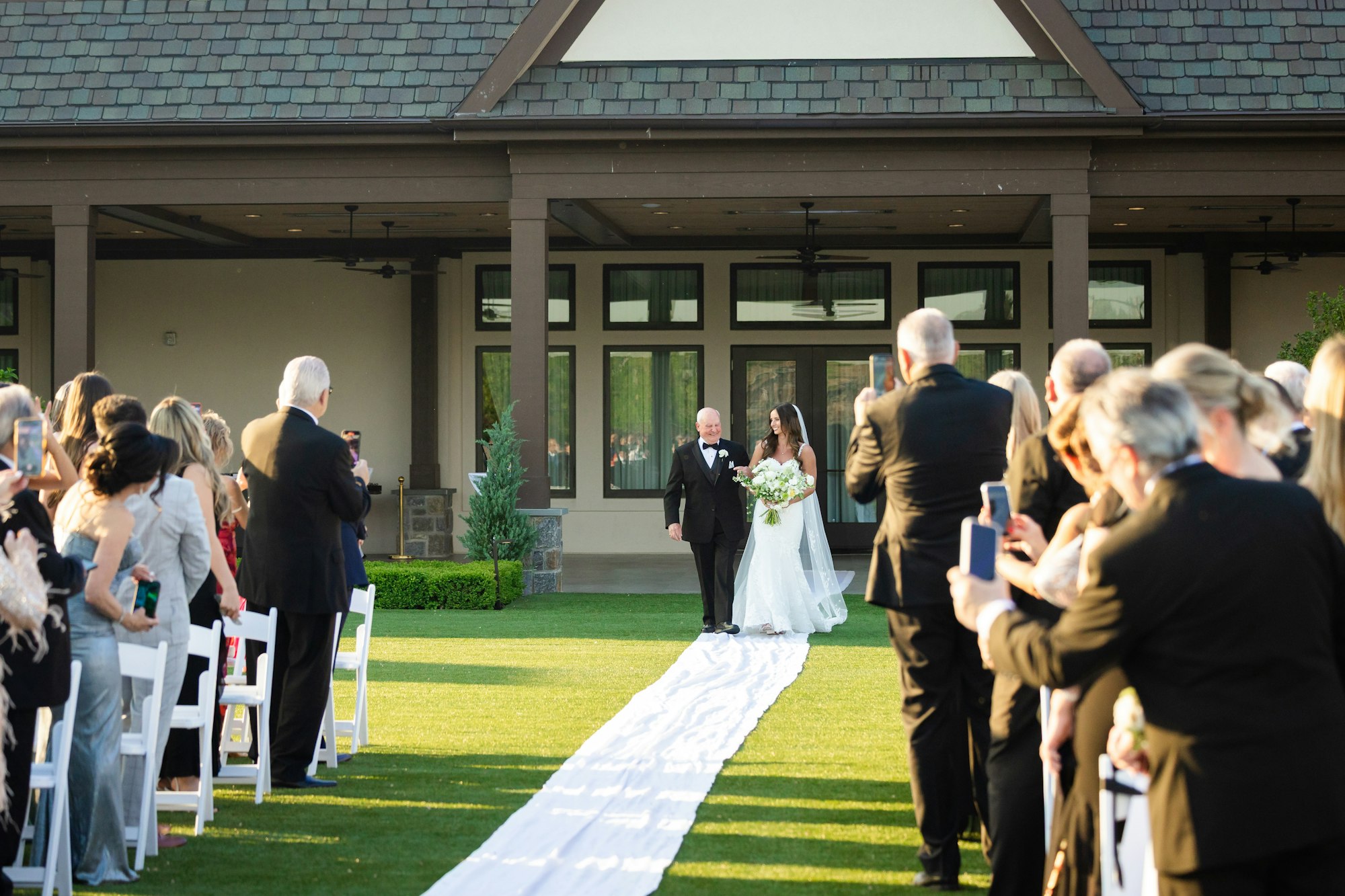 A covered terrace ceremony with a white aisle runner at TillingHouse